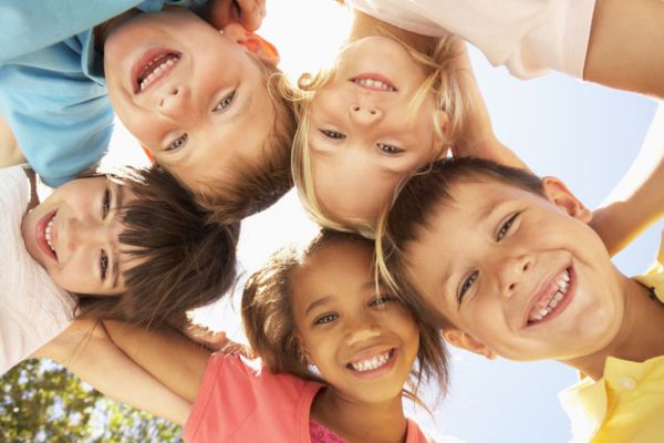 Kinder stehen im Kreis und stecken die Köpfe zusammen