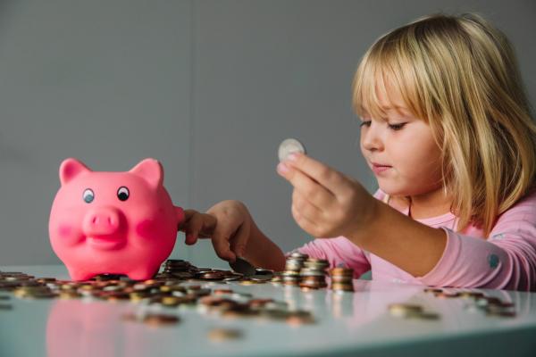 Kind steckt Geld ins Sparschwein