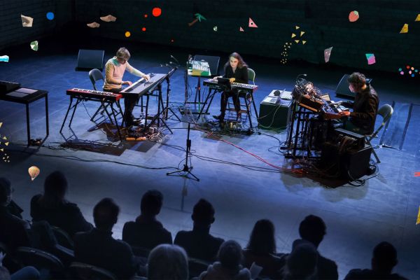 Drei Musiker:innen sind mit ihren Instrumenten auf der Bühne.