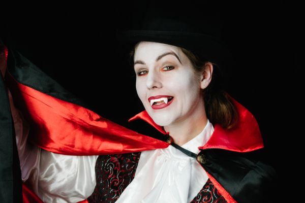 Vampir mit scharfen Zähnen und rotem Umhang