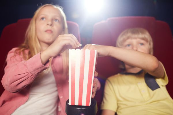 Zwei Kinder in Kinosesseln mit Popcorn